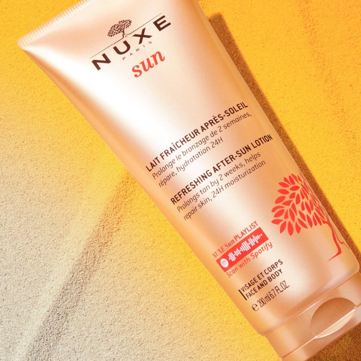Nuxe Sun Refreshing After-Sun Lotion 200 ml forlænger kuløren i en bronzefarvet tube på en baggrund af sand