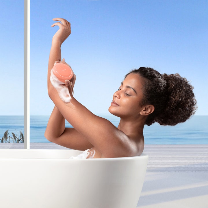 FOREO LUNA 4 body Peach Perfect 1 stk eksfolierende kropsbørste brugt af kvinde i badekar med hvidt skum