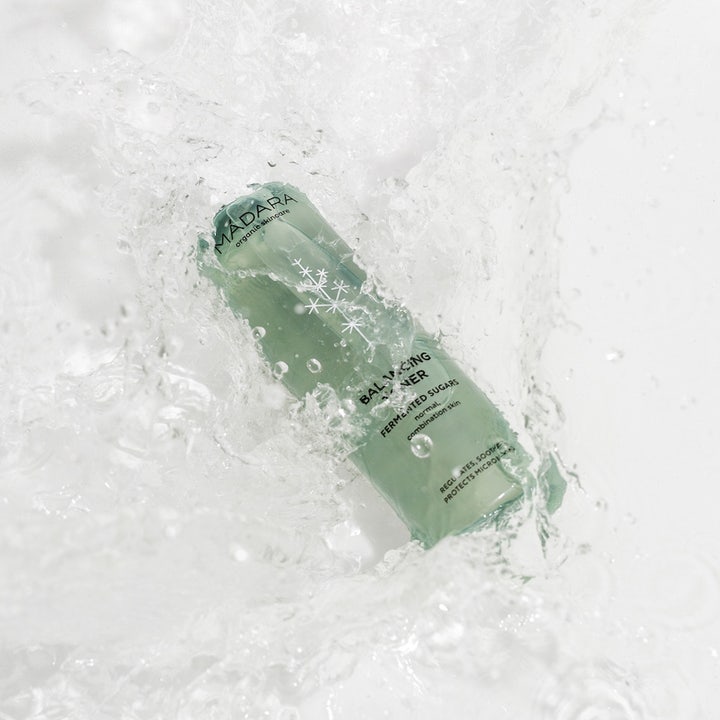 MÁDARA Balancing Toner 200 ml balancerende ansigtsvand i grøn flaske omgivet af forfriskende vandsprøjt