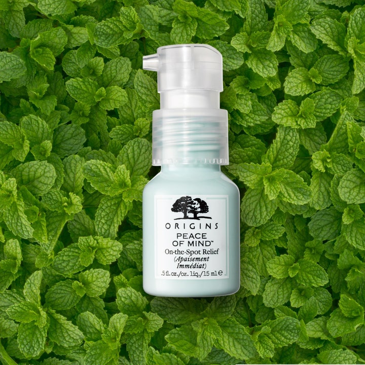 Origins Peace Of Mind On The Spot Relief 15 ml beroligende spot treatment i lyseblå flaske på grønne mynteblade