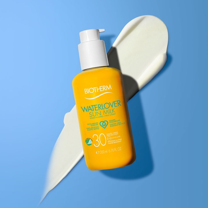 Biotherm Waterlover Sun Milk SPF30 200 ml solcreme på lyseblå baggrund med cremet hvid tekstur bag den gule flaske