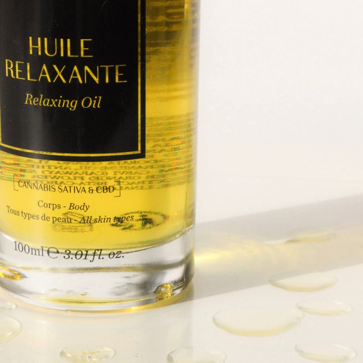 Codage Paris Relaxing Oil 100 ml beroligende kropsolie med CBD i glasflaske ved siden af gyldne oliedråber.