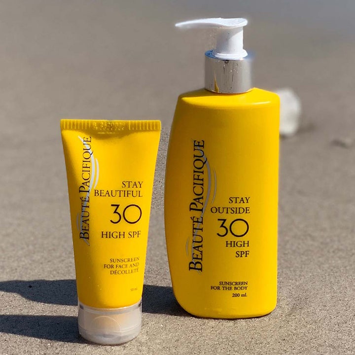 Beauté Pacifique Stay Outside SPF30 200 ml solcreme i gul pumpeflaske og tube på en sandstrand