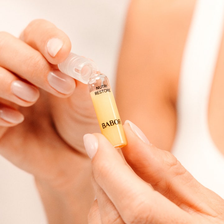 Babor Nutri Restore Ampoule 14 ml serum drypper en gylden olieagtig konsistens ned i en håndflade