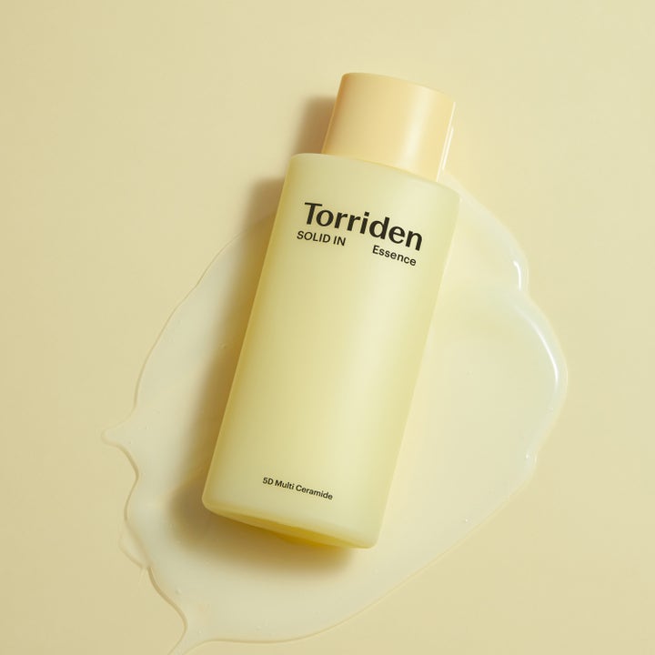 Torriden SOLID-IN All Day Essence 100 ml fugtgivende essence i gul flaske placeret i cremet tekstur med ceramider.