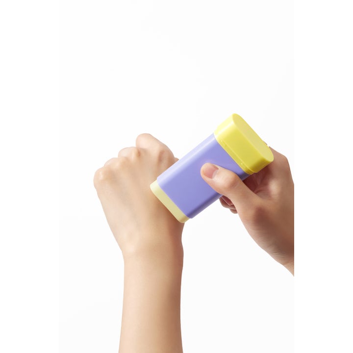 By Wishtrend Pore Smoothing Bakuchiol Sun Stick 18 g solcreme påføres direkte på huden fra den lilla og gule stift.