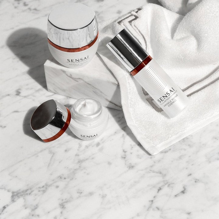 Sensai Cellular Performance Wrinkle Repair anti-age hudplejesæt med hvid creme og essence på marmor