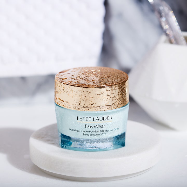 Estée Lauder DayWear 50 ml fugtgivende dagcreme i lyseblå glaskrukke med guldlåg dækket af friske vanddråber.