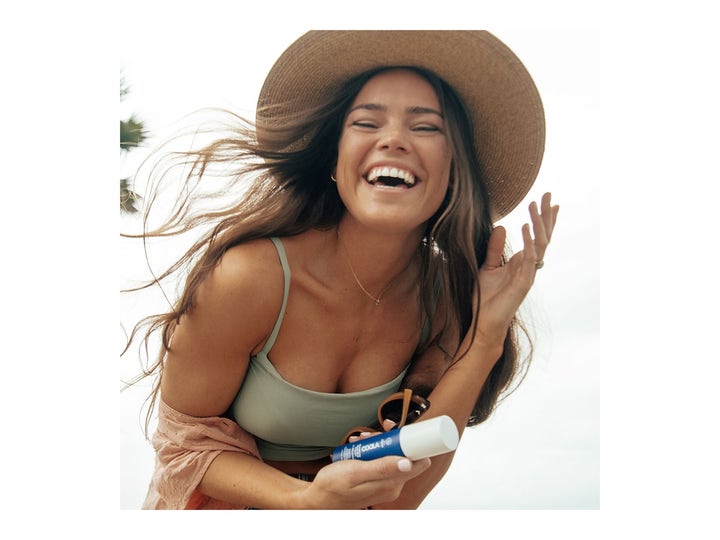 COOLA Refreshing Water Mist SPF15 50 ml fugtgivende ansigtsspray holdt af en smilende kvinde i stråhat