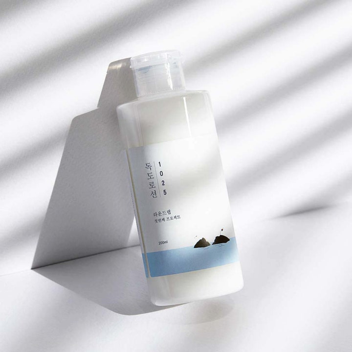 Round Lab 1025 Dokdo Lotion 200 ml fugtgivende lotion i hvid flaske med blå ø-illustration i et skyggespil
