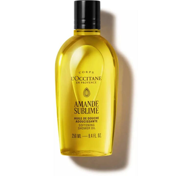 L'Occitane Almond Shower Oil 250 ml blødgørende badeolie i gennemsigtig flaske med gylden tekstur og sølvlåg.