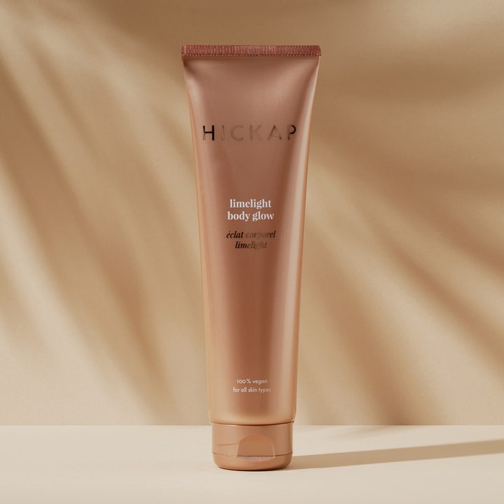 Hickap Limelight Body Glow 150 ml giver huden en varm glød i en bronzefarvet tube mod en solgylden baggrund