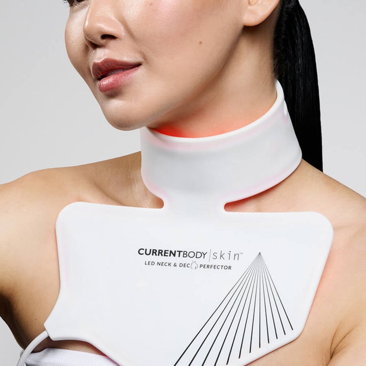 Currentbody Skin Neck and Dec Perfector hvid LED-maske i blød silikone der lyser rødt på hals og bryst.