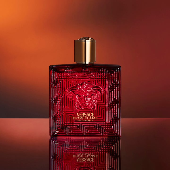 Versace Eros Flame 100 ml aftershave på rød glasflakon med guldlogo mod varm orange baggrund