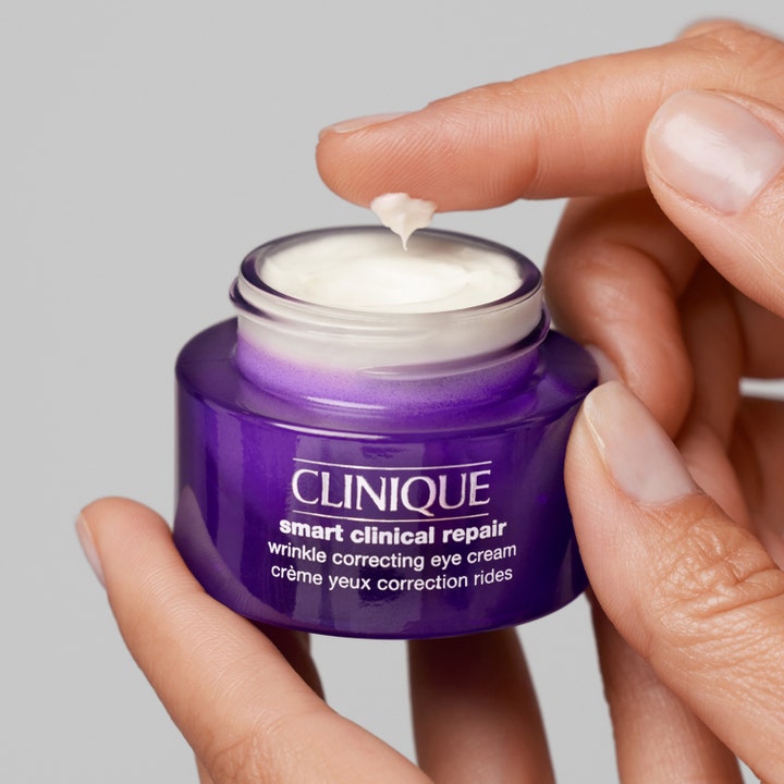 Clinique Smart Clinical Repair 15 ml rynkekorrigerende øjencreme i lilla krukke med hvid creme på en fingerspids