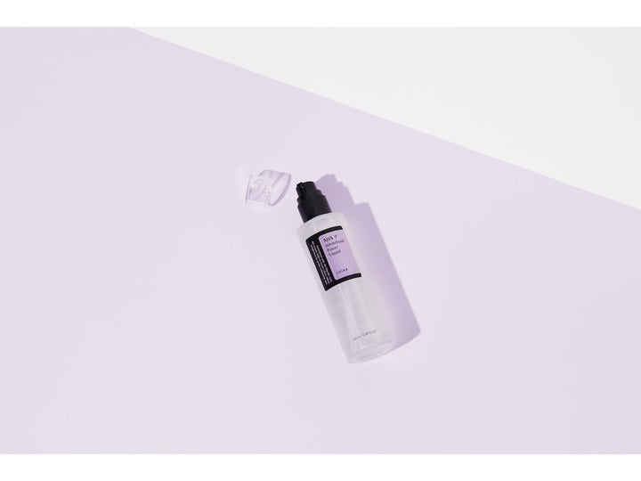COSRX AHA 7 Whitehead Power Liquid 100 ml eksfolierende toner i frostet flaske med sort pumpe på lilla baggrund