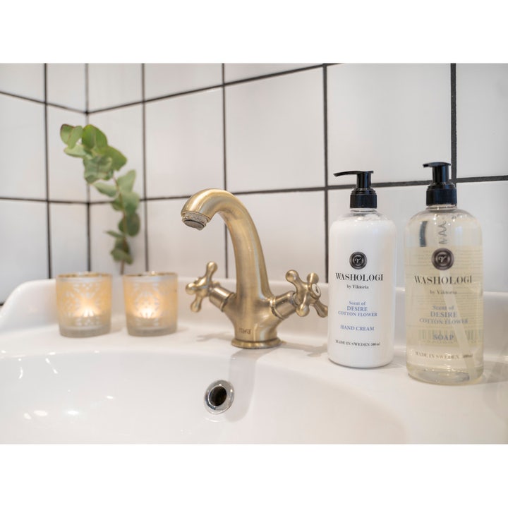 Washologi Hand Cream Scent of Desire 500 ml plejende håndcreme i hvid pumpeflaske ved en elegant messingvandhane.