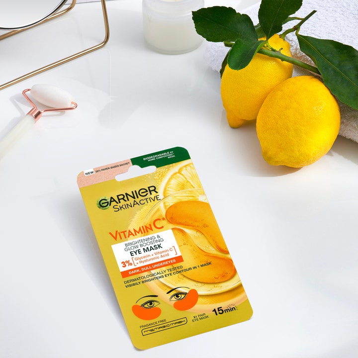Garnier Skin Active Vitamin C 5 g øjenmaske mod mørke rande i gul pakke med friske citroner og en jade-rulle.