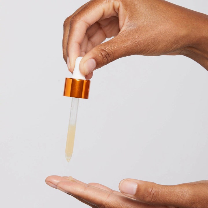 Dermalogica AGE smart Biolumin-C Serum 30 ml lysnende serum dryppes fra en glaspipette med orange låg ned i en hånd