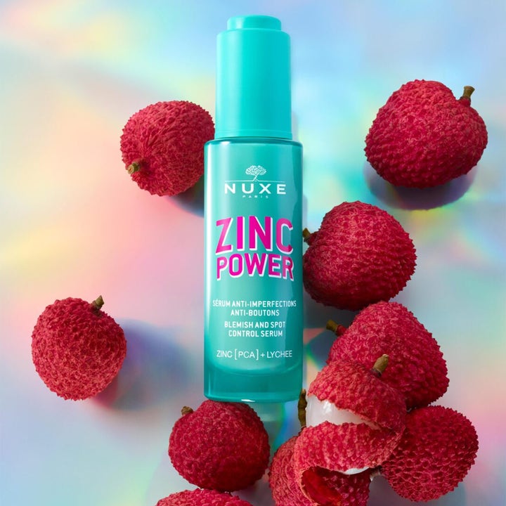 Nuxe Zinc Power Serum 30 ml mod urenheder i turkis flakon omgivet af friske litchifrugter