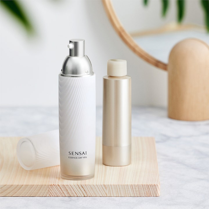 Sensai Essence Day Veil 40 ml fugtgivende dagcreme i hvid flaske med rillet tekstur og sølvpumpe på træ