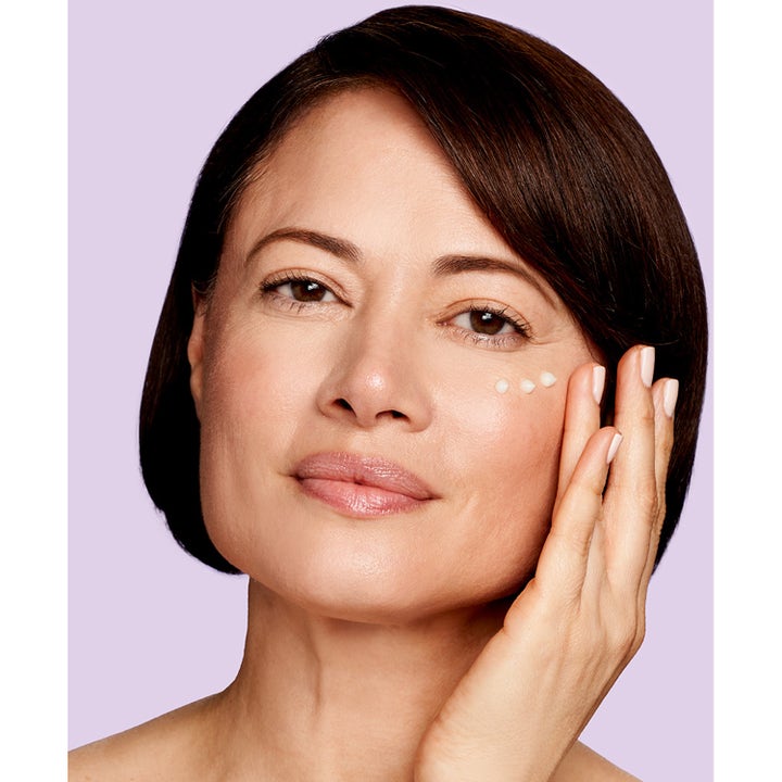 Exuviance Age Reverse Eye Contour 15 g opstrammende øjencreme påført som hvide prikker under øjet på en kvinde