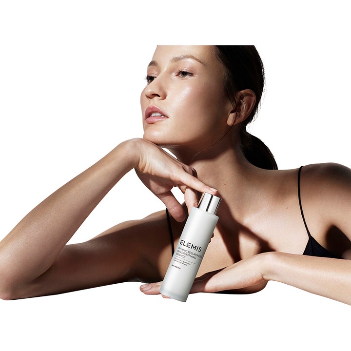 Elemis Dynamic Resurfacing Skin Smoothing Essence 100 ml giver glød vist med model og hvid flaske