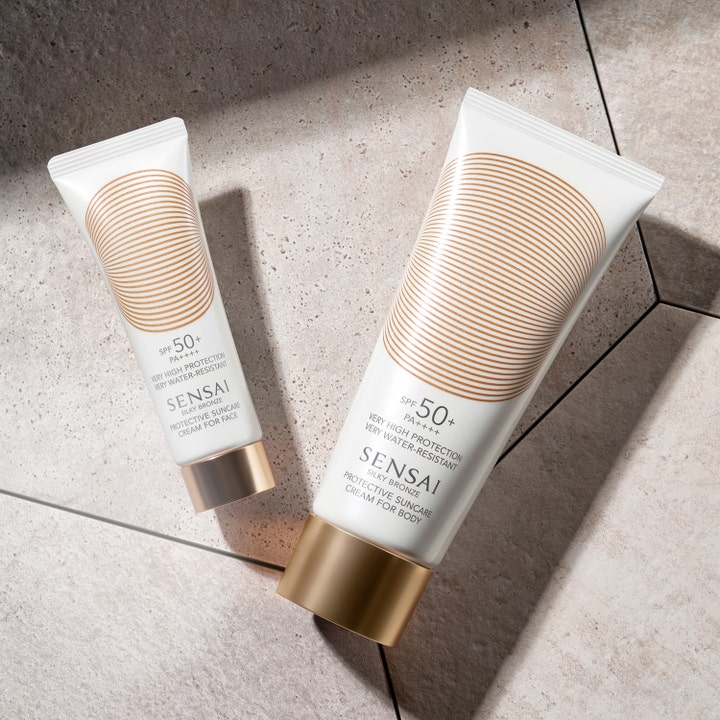 Sensai Silky Bronze Protective Cream Face SPF50+ 50 ml solcreme i hvid tube med gulddetaljer på grå stenfliser.