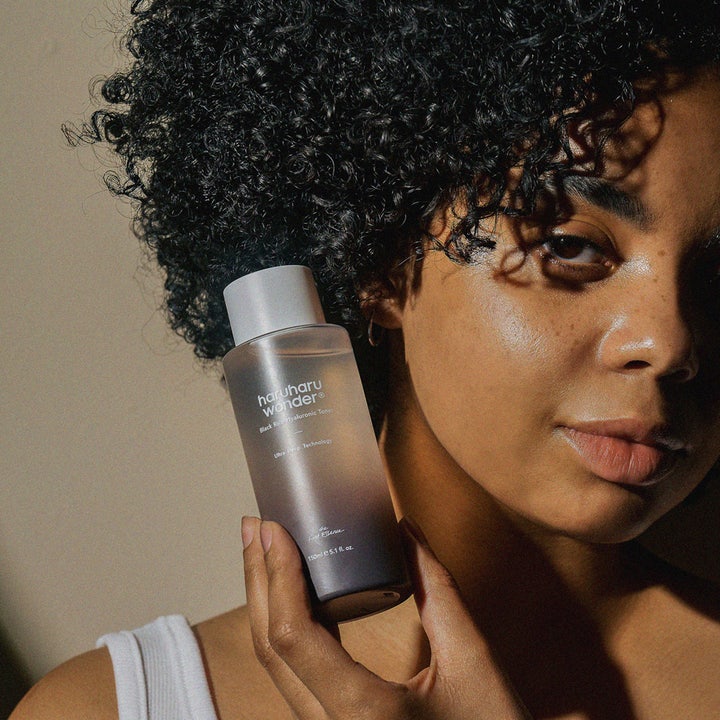 haruharu wonder Black Rice Hyaluronic Toner 150 ml fugtgivende toner holdes af kvinde med mørkt krøllet hår