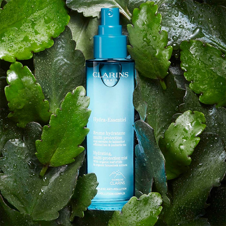 Clarins Hydra-Essentiel Hydrating multi protection mist 75 ml fugtgivende ansigtsmist i blå flaske blandt grønne blade