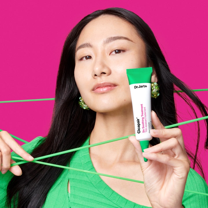 Dr.Jart+ Cicapair So Soothing Treatment 30 ml beroligende hudpleje i hvid tube holdt af kvinde mod pink baggrund.