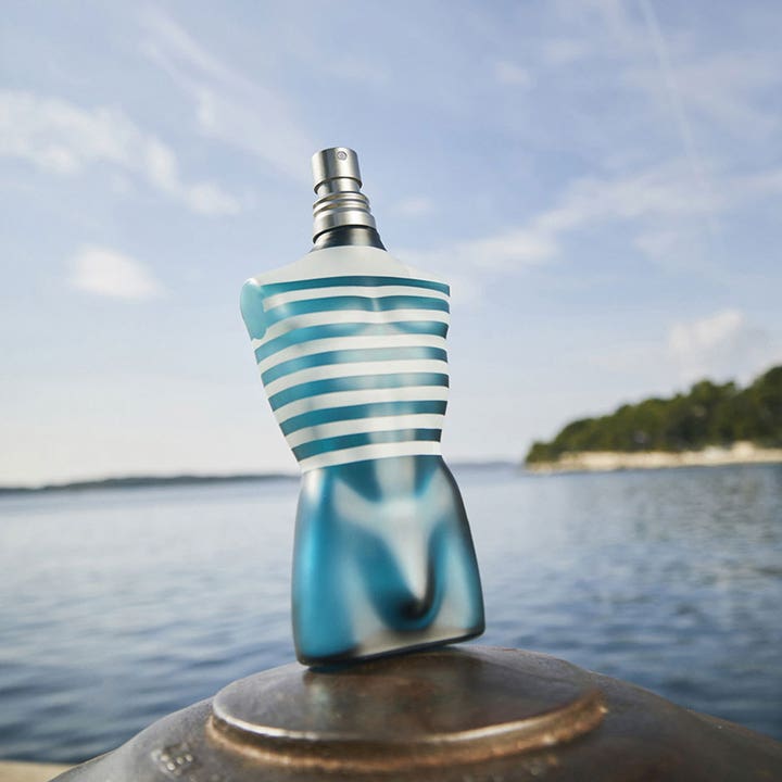 Jean Paul Gaultier Le Male After Shave 125 ml i ikonisk blå torso-flakon foran havet som giver en frisk følelse.