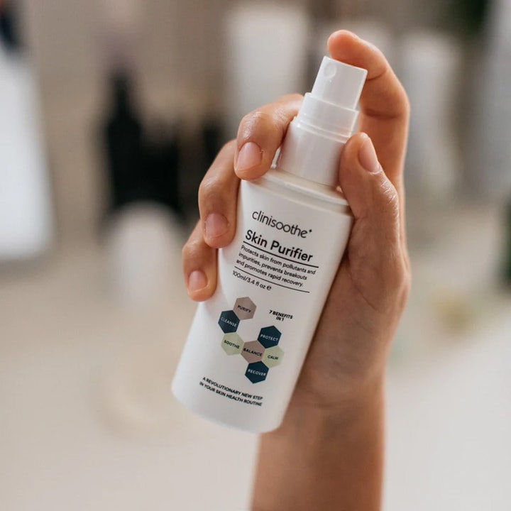 Clinisoothe Skin Purifier Spray 100 ml beroligende toner i hvid sprayflaske holdt i en hånd der renser huden.