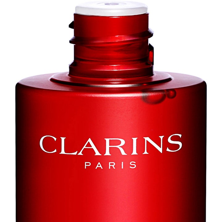 Clarins Super Restorative Treatment Essence 200 ml genopbyggende essence i rød flakon med hvidt logo og lille dråbe