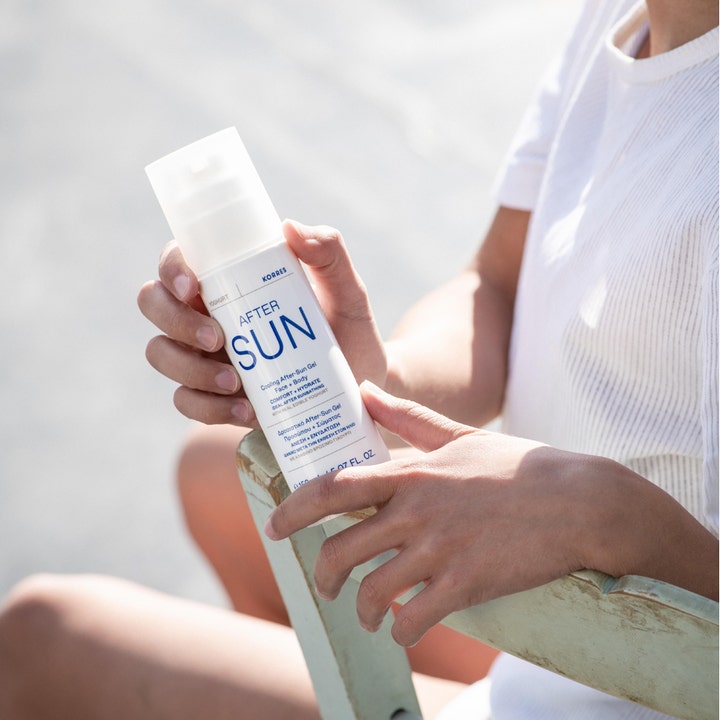 Korres Yoghurt Cooling After-Sun Gel 150 ml kølende aftersun i hvid pumpeflaske holdt af en person i solrigt miljø.