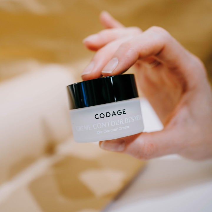 Codage Paris The Eye Contour Cream 15 ml øjencreme mod mørke rande i en matteret glaskrukke holdt af en hånd.