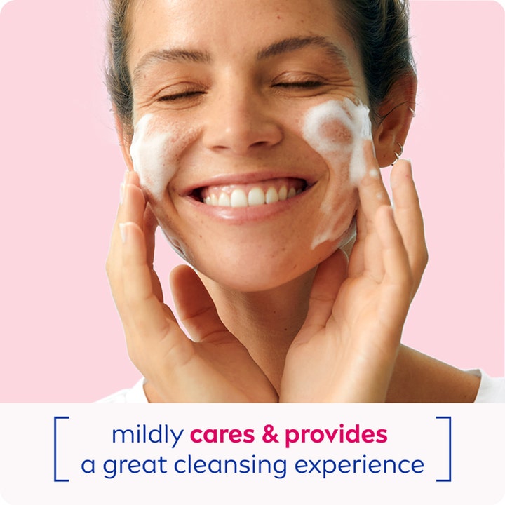 NIVEA Cleansing Mousse Caring 150 ml rengøringsskum plejer mildt vist på en smilende kvinde med hvidt skum på kinderne.