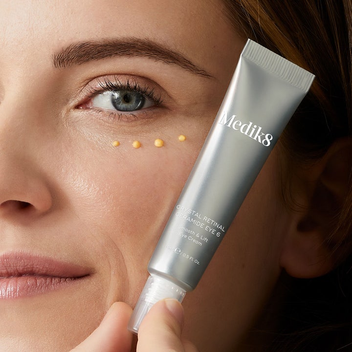 Medik8 Crystal Retinal Ceramide Eye 3 15 ml opstrammende øjencreme påført som gule dråber under øjet fra en sølvtube