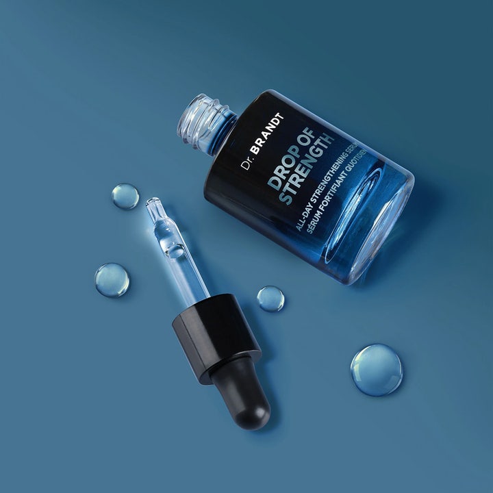Dr Brandt Drop Of Strength 30 ml styrkende ansigtsserum i mørkeblå glasflaske med pipette og dråber af klar tekstur