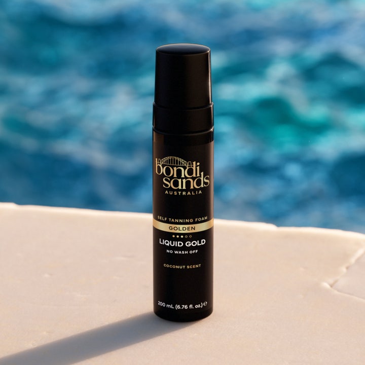 Bondi Sands Liquid Gold Self Tanning Foam 200 ml selvbruner i sort flaske placeret ved en blå swimmingpool
