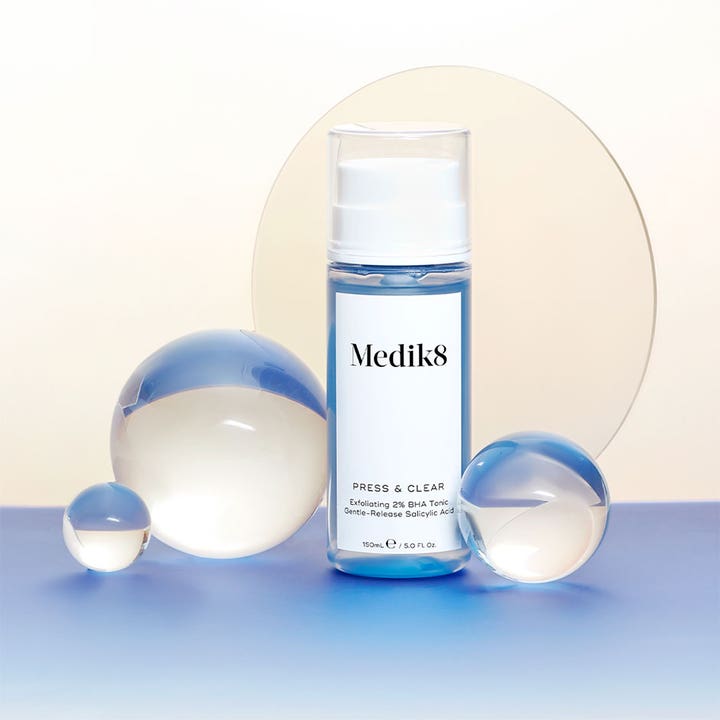 Medik8 Press & Clear 150 ml eksfolierende 2% BHA toner i blå flaske stylet med gennemsigtige glaskugler